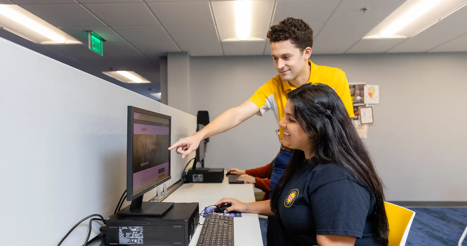 Admissions staff member assisting student with registration on computer
