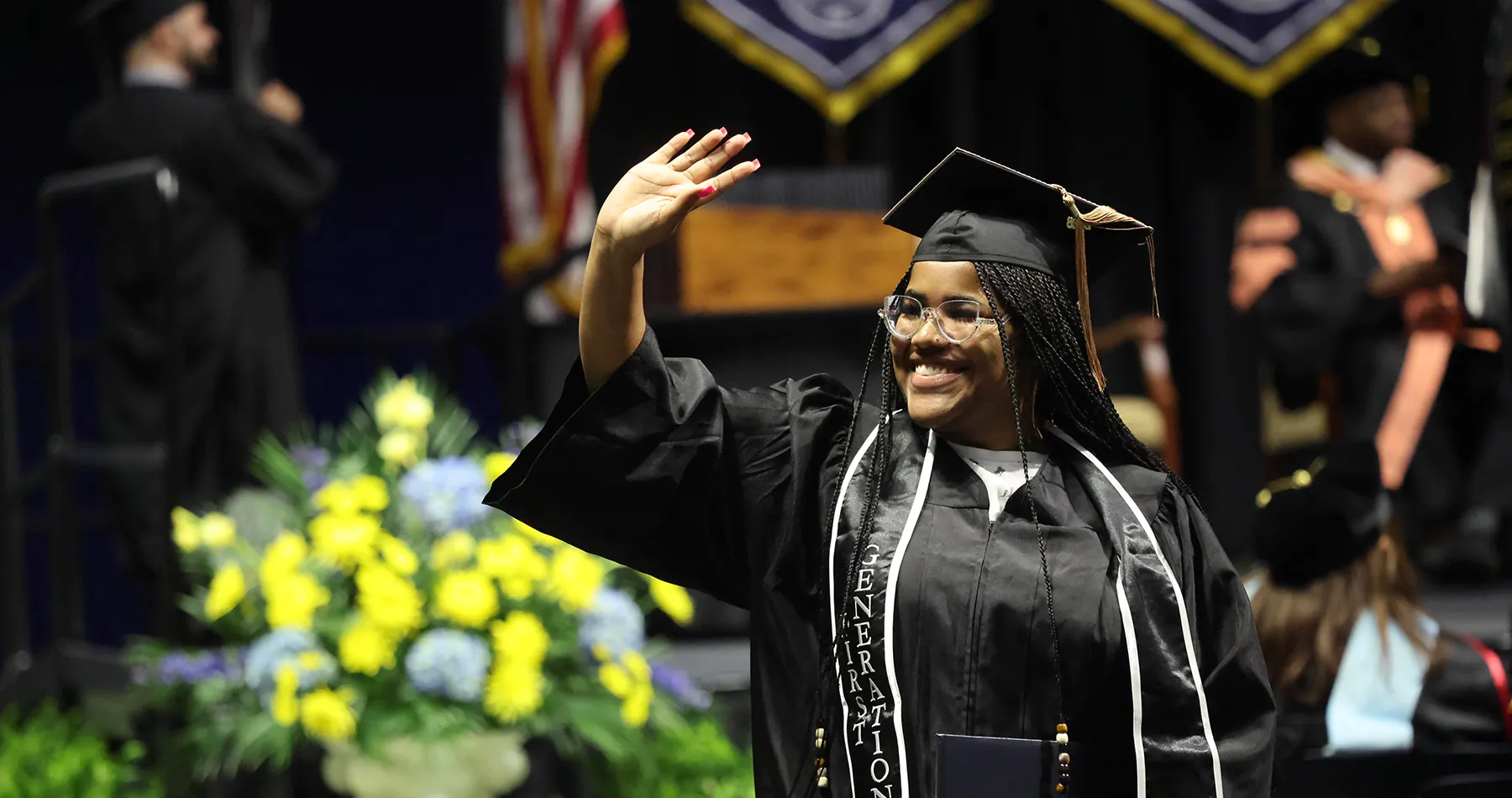 Graduate smiling and waving to crowd