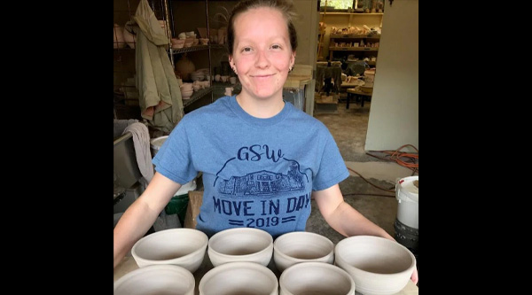 Art student with ceramic bowls for event