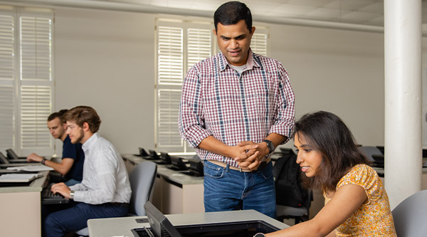 student working on computer with faculty assistance