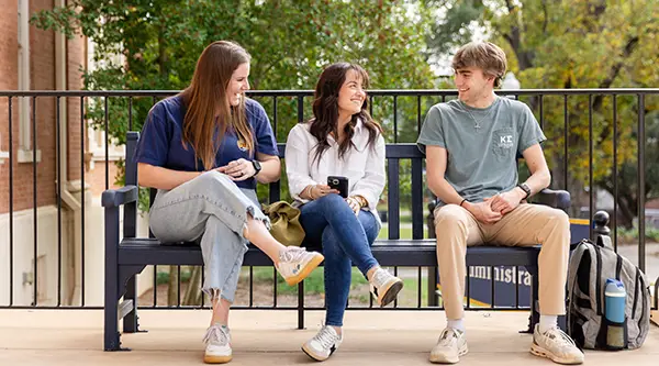 Students sitting on a bench laughing 