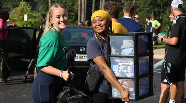 Two female students helping move in furniture