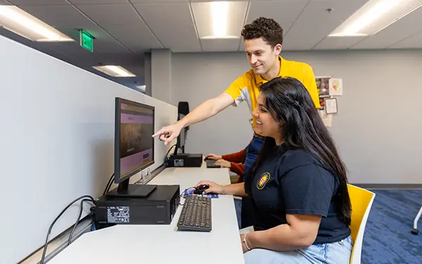 Admissions staff member assisting student on computer
