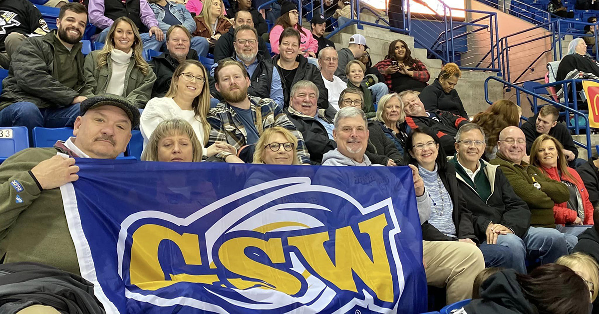 alumni hold GSW flag in hockey stands