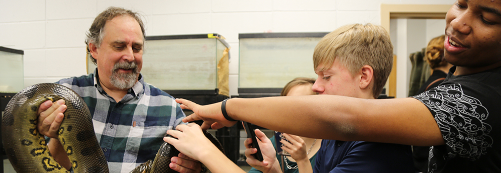 students touch green anaconda in biology lab
