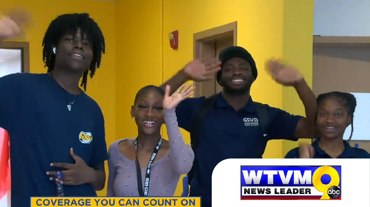 students in GSW shirts wave to camera