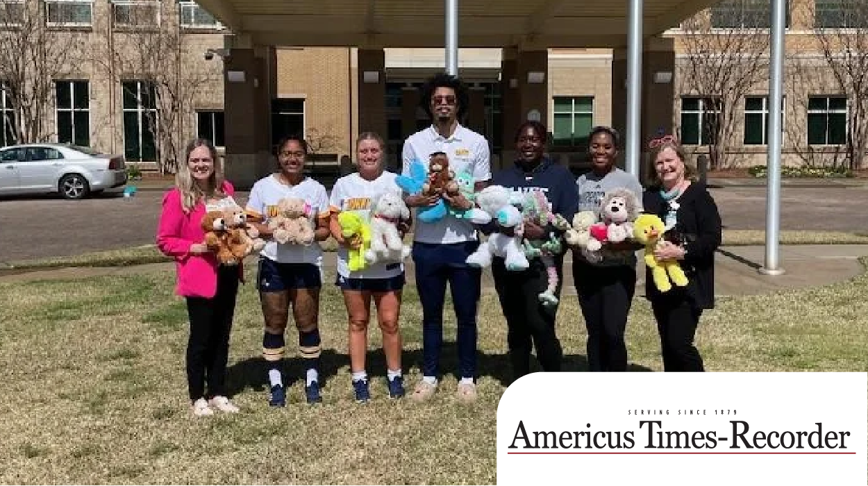 student athletes hold teddy bears at hospital