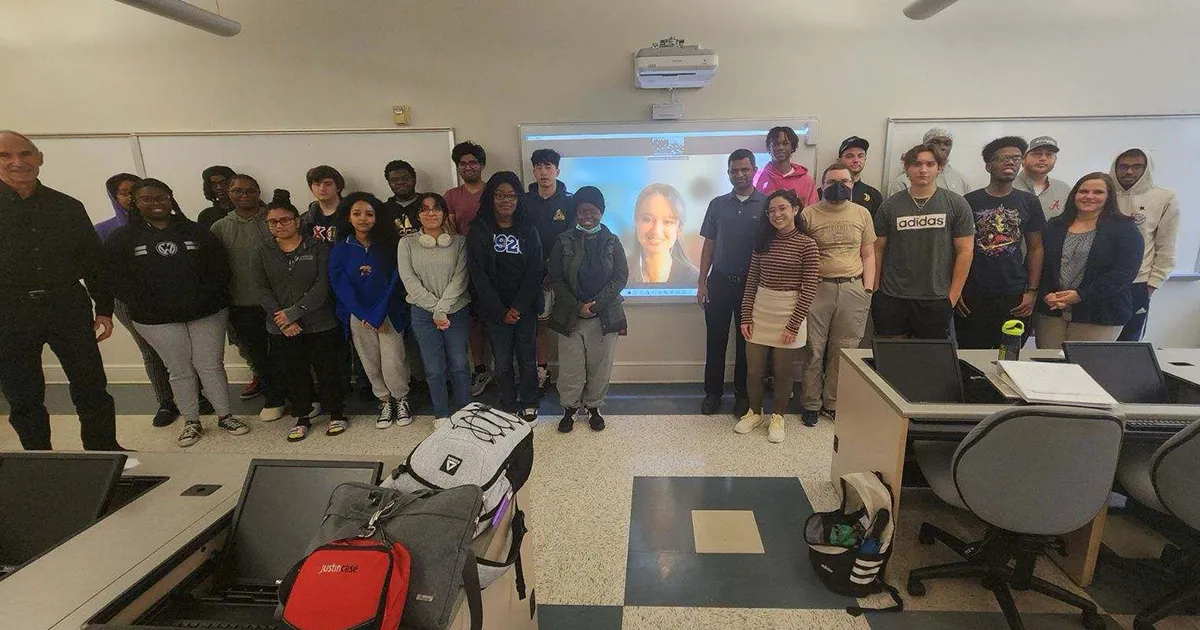 students pose with speaker on projector screen