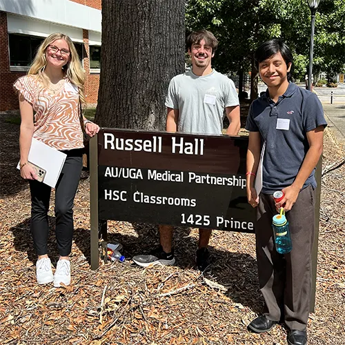 students in front of UGA building sign