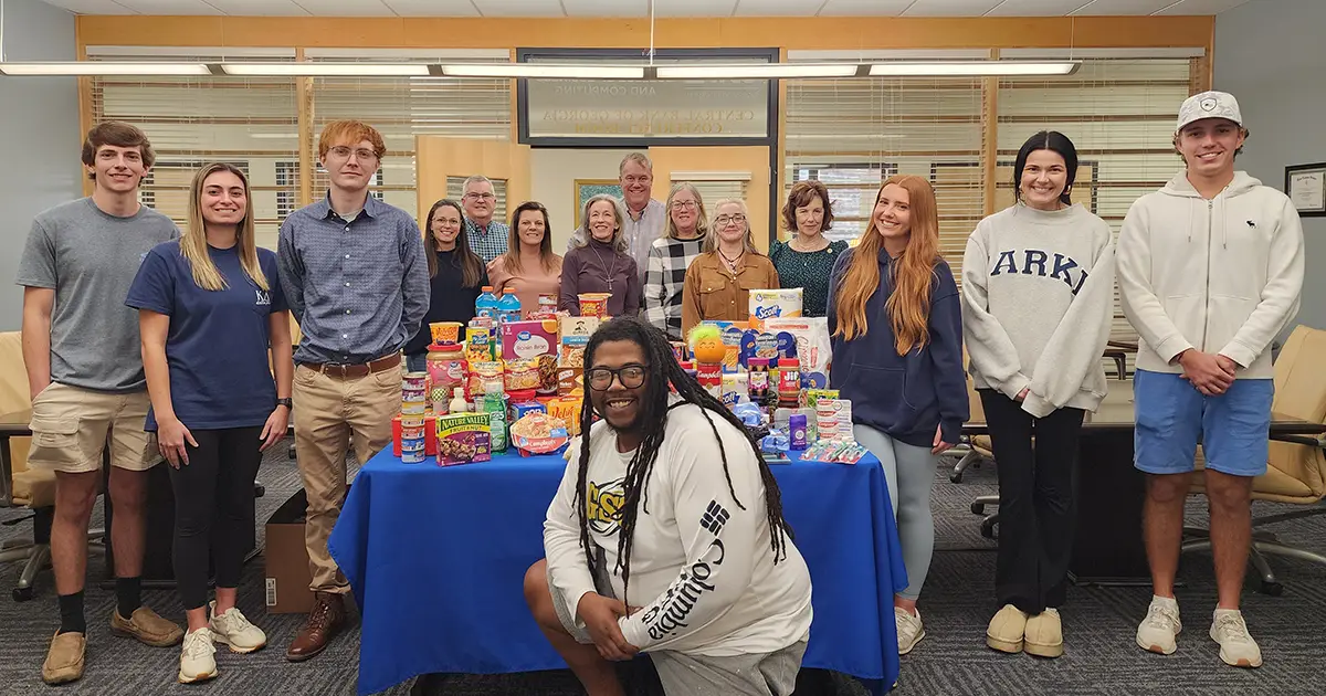 students and faculty pose among food donations