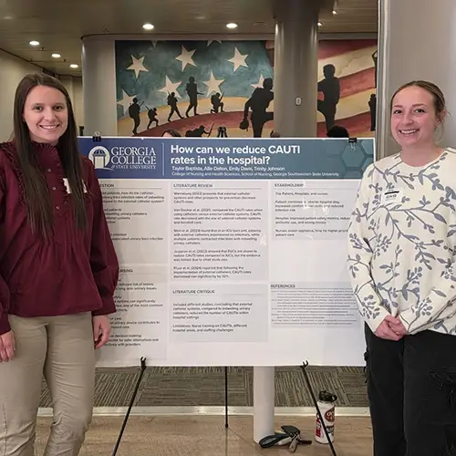 Taylor and Emily pose next to their poster