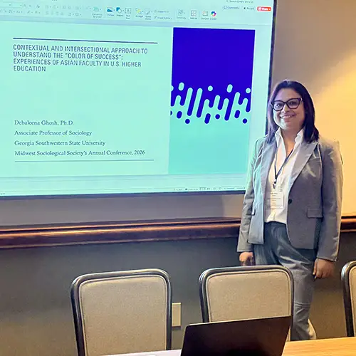 Dr. Ghosh stands next to her presentation