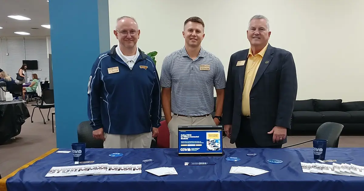 professors stand at GSW table