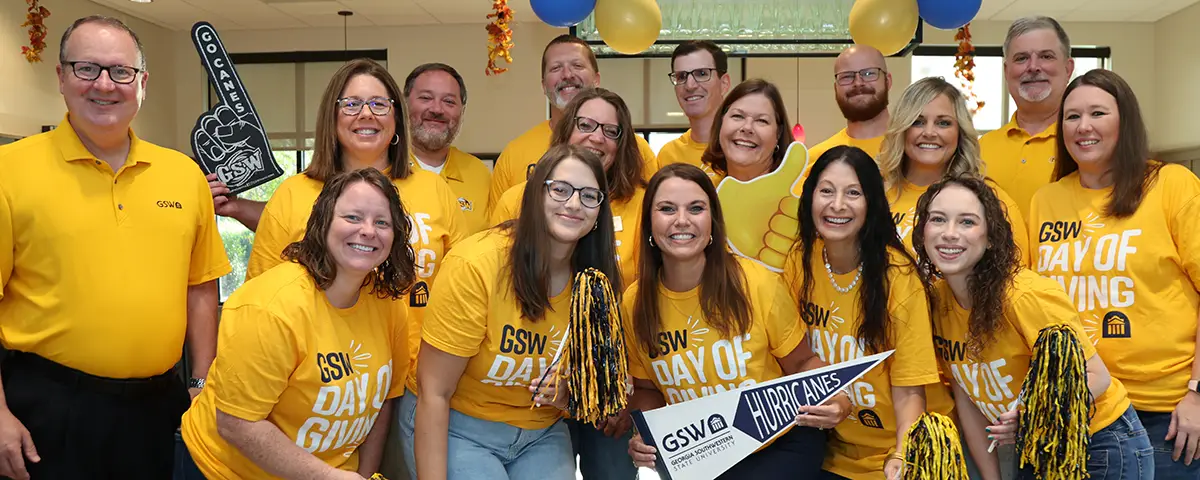 staff in gold shirts pose with GSW props