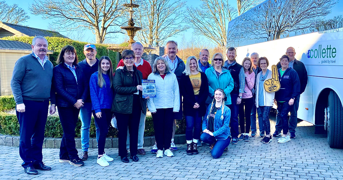 alumni group stand outside tour bus