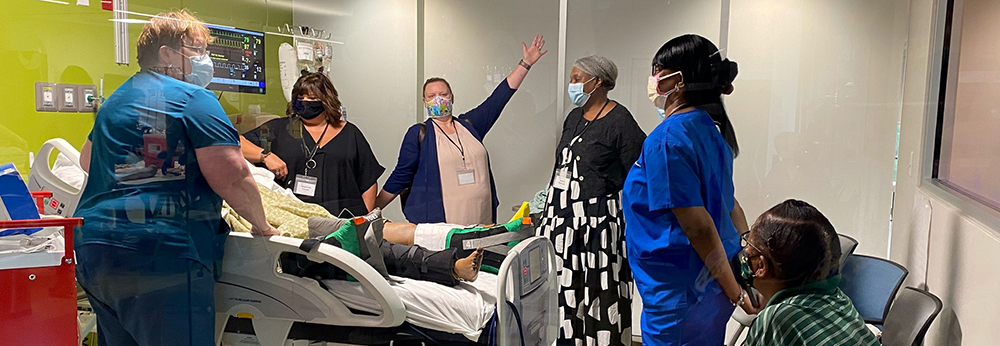 group stands around simulation hospital room
