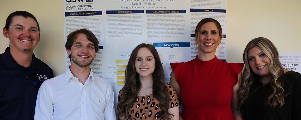 Five students in front of symposium research poster