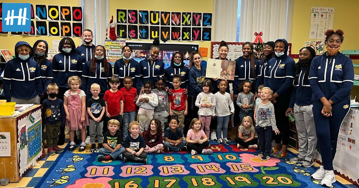 women's basketball players pose with elementary class