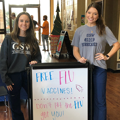 students stand with flu clinic sign