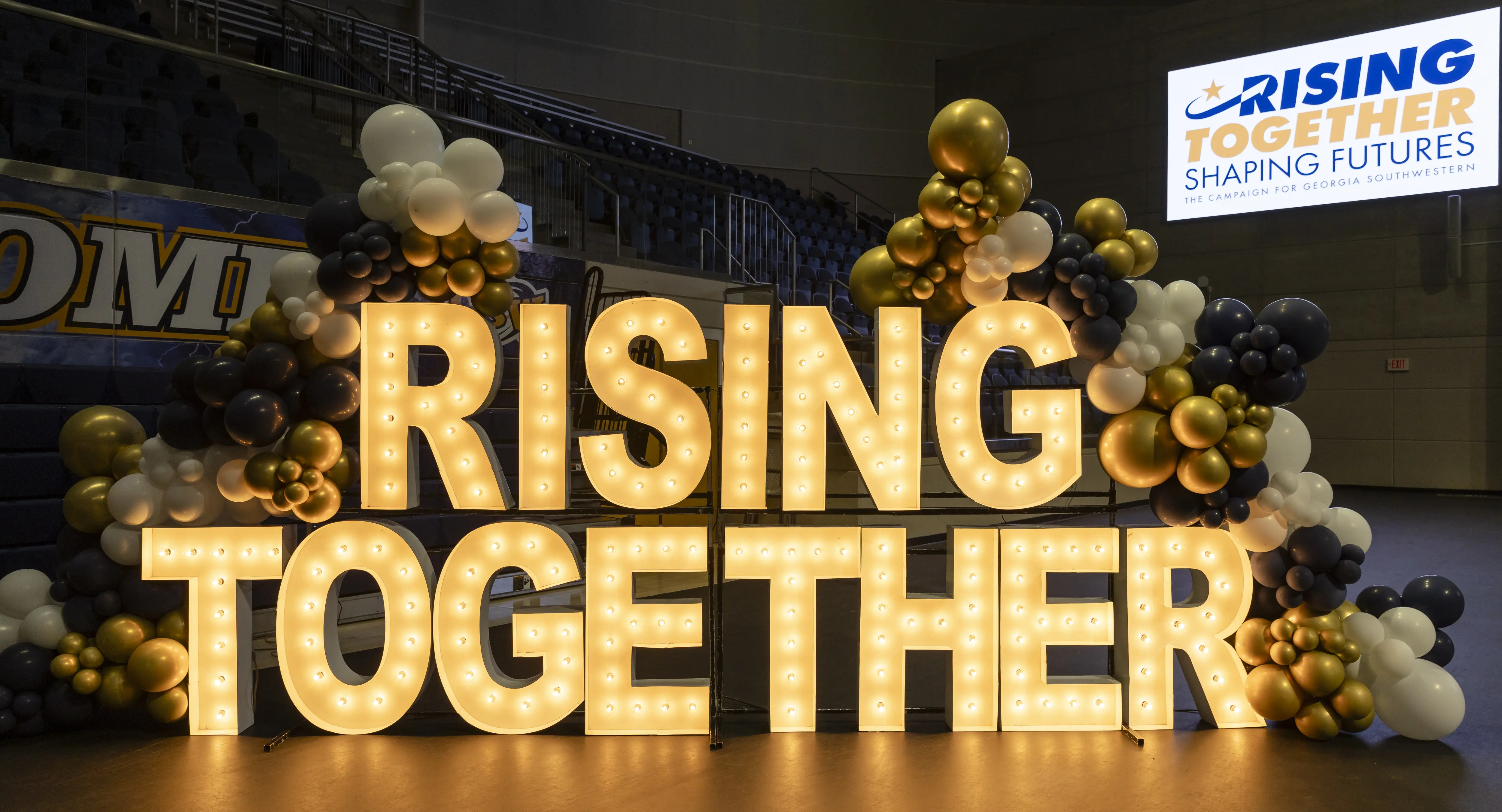A big glowing sign that says Rising Together.