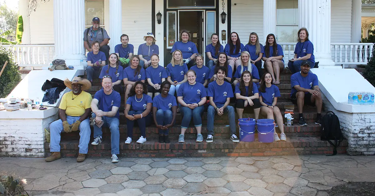 students pose in front of historic home