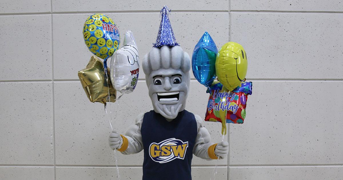 Surge wears birthday hat and hold balloons