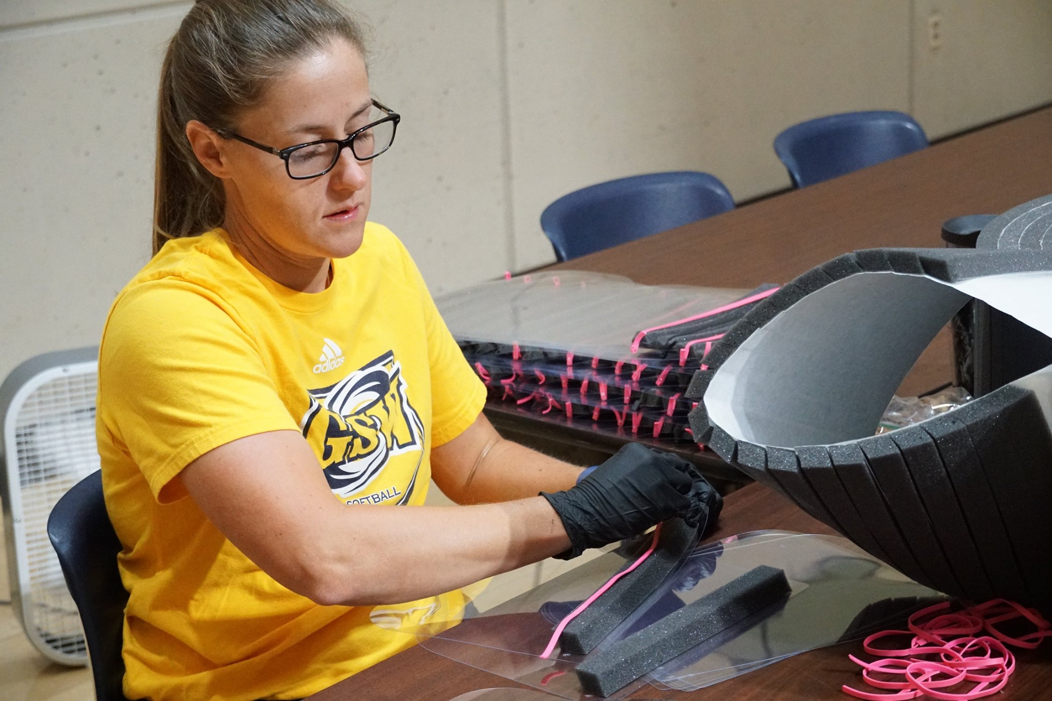 woman assembling face shields