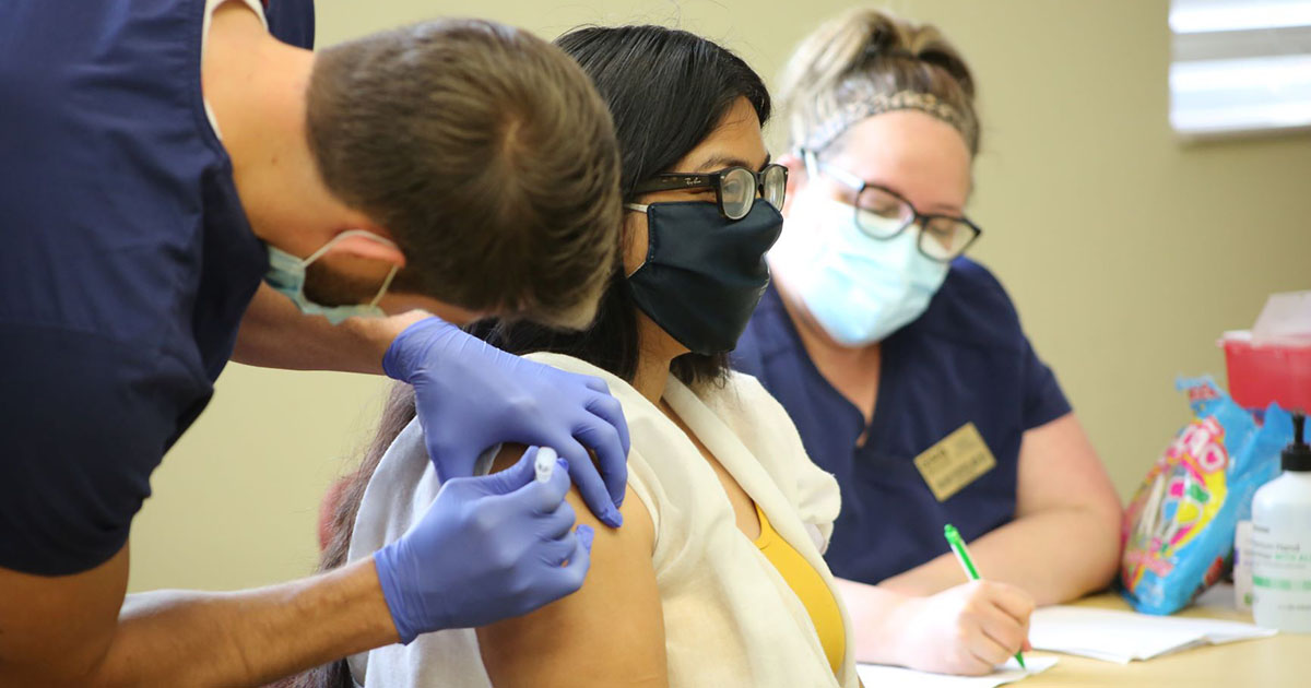 Staff member receives vaccine from nursing student