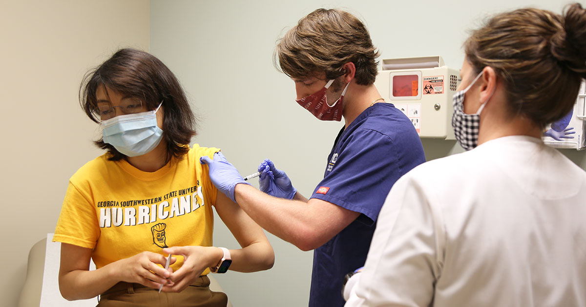 woman receives vaccine from male nursing student