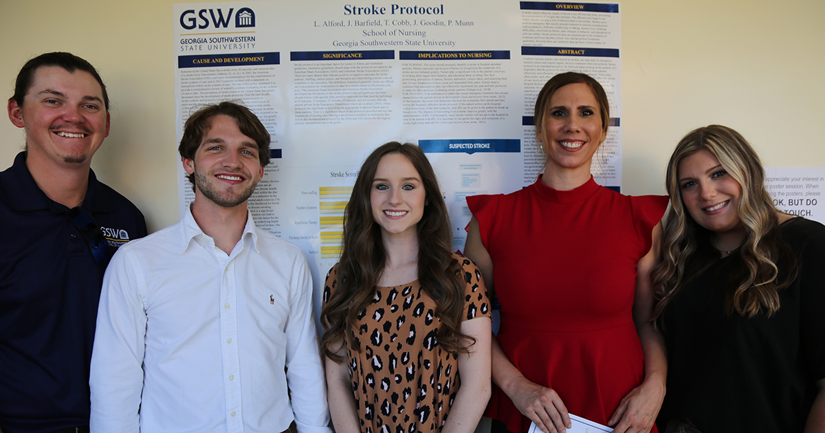 nursing students stand in front of poster