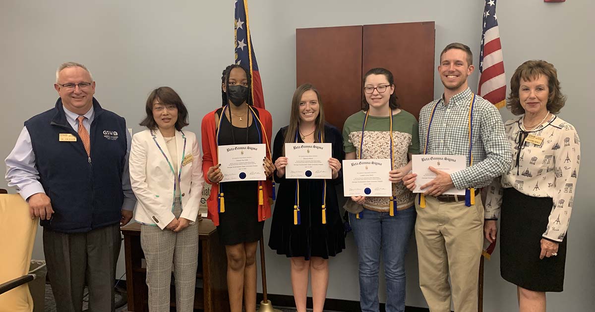 students hold honor society certificates alongside professors