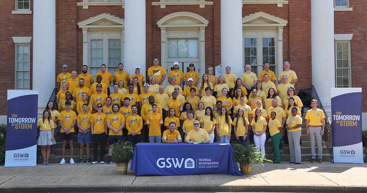 faculty, staff, and students wear gold on the front steps of the Wheatley Administration Building