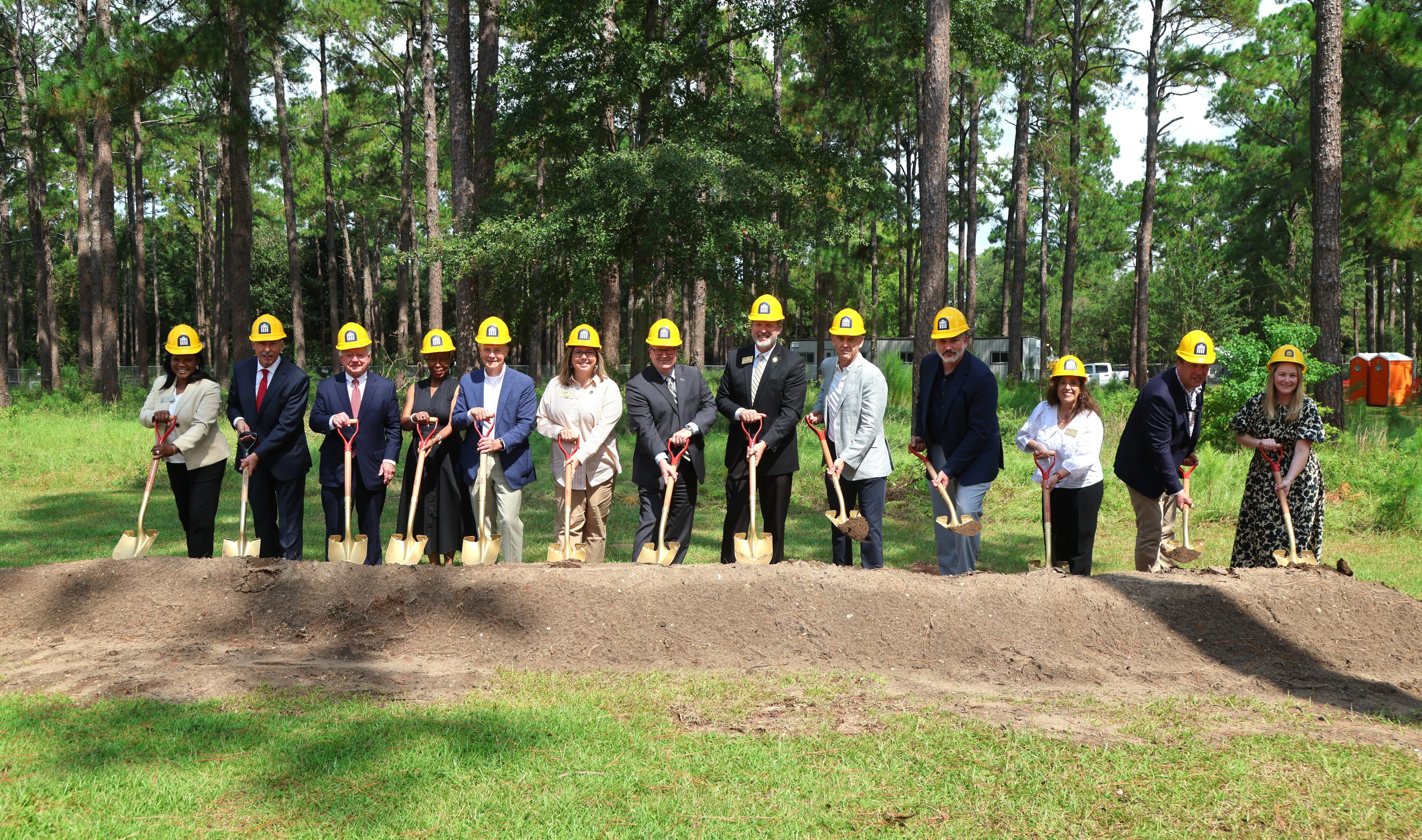 individuals in hard hats and shovels break ground