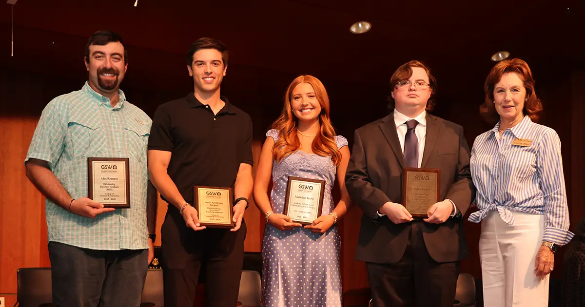 four students pose with award plaques