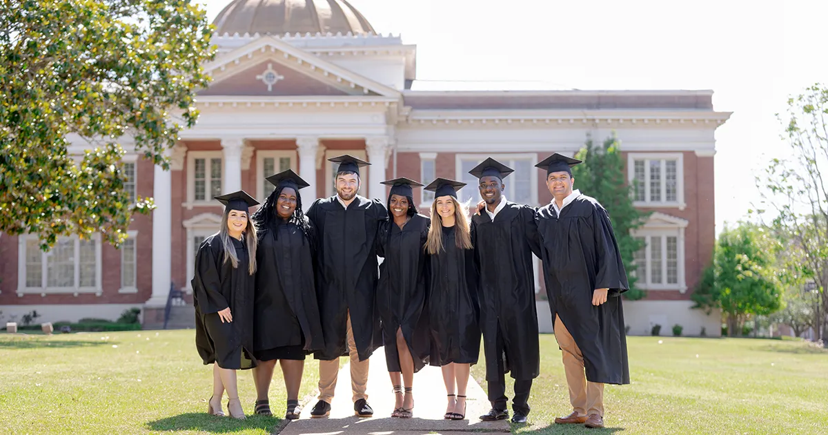 Students in cap and gown in front of Admin building