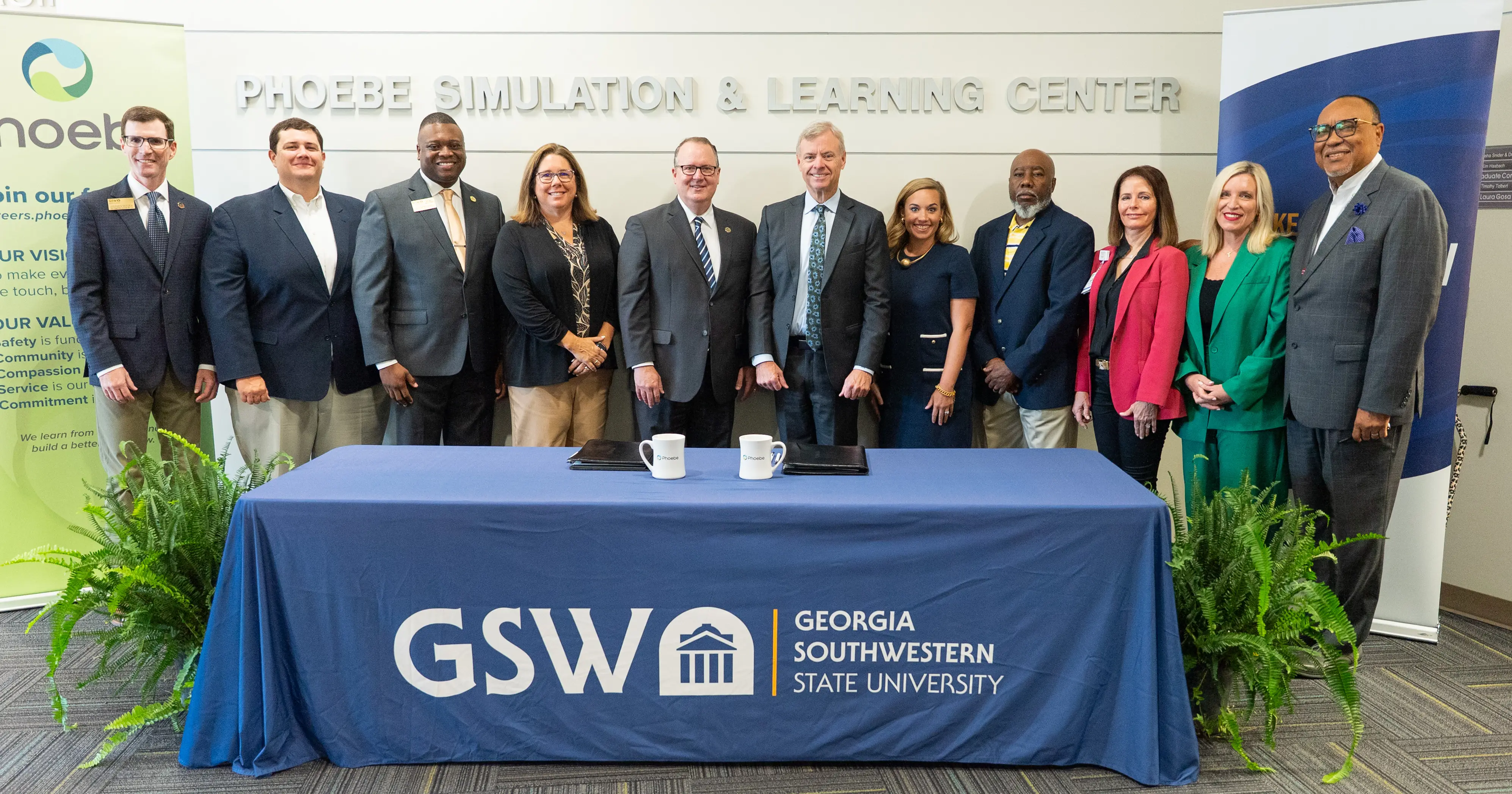  Georgia Southwestern State University President Kerry Palmer (on the left) and Phoebe Putney Health System President & CEO Scott Steiner signing a new partnership agreement, as well as other GSW and Phoebe leaders at the signing ceremony.